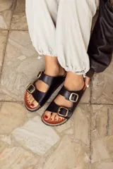 Sandalias negras con dos tiras anchas ajustables con hebillas doradas. Plataforma de corcho y suela de goma.