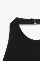 Top negro con cuello halter y espalda descubierta. Presenta detalle de combinación de tejidos en contraste con laterales blancos y bajo acabado en peplum.