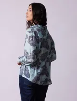 Camisa de gasa estampada a rayas verticales de color celeste, blanco, naranja y marrón. Tiene cuello con solapa, escote en V, abertura central con botones, bolsillo aplicado en el pecho y terminación anudada en la parte delantera.