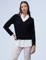 Buzo combinado con torso de tejido de punto fino en color negro y detalles de cuello y ruedo en gasa blanca que simulan una camisa debajo. Presenta escote en V y mangas largas.
