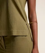 Musculosa verde oliva de piquet con escote en pico, breteles anchos, pequeñas aberturas laterales y bajos con pespuntes.