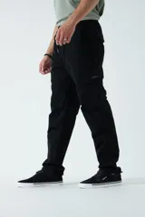 Pantalón cargo color beige, con cintura elástica ajustable con cordón, bolsillos laterales con cierre y bolsillos cargo con solapa.