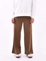 Pantalón ancho de tejido liso color marrón, con cintura elástica y corte recto que cae suelto hasta el tobillo.