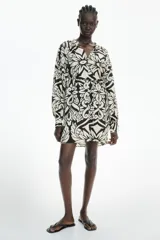 Vestido corto en mezcla de viscosa con estampado floral en blanco y negro, cuello mao fruncido y abertura en V adelante. Modelo de corte holgado con cinturón extraíble para atar en la cintura, y mangas globo largas de corte raglán con abertura y botón en los puños.