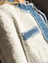 Chaqueta Nanette en tejido tweed color blanco y denim azul. Tiene cuello a la base, abertura central, bolsillos delanteros, puños con aplique de botones perlados, terminación desflecada y forro interno.
