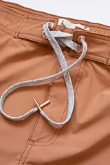 Short de baño color ladrillo con cintura elástica y cordón ajustable. Presenta una franja lateral blanca estilo esmoquin, dos bolsillos laterales y uno trasero con cierre.