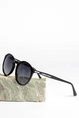 Lentes de sol unisex con montura redonda negra y lentes degradadas de gris a transparente.
