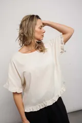 Blusa color crudo, de corte suelto, con mangas cortas y volados en ruedo y mangas.