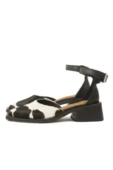Sandalias bajas de cuero con estampado animal print de vaca en blanco y negro, con pulsera al tobillo y taco cuadrado.