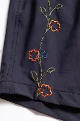 Short de baño azul marino con bordado de enredadera en la pierna izquierda, cintura elástica con cordón ajustable, bolsillos laterales y bolsillo trasero con cierre.