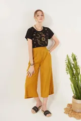 Pantalón crop color mostaza, de corte ancho y tiro alto, con cintura elastizada.