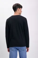 Remera de color negro, de corte clásico, con manga larga y bolsillo frontal.
