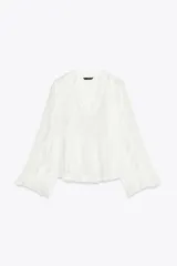 Camisa blanca de cuello redondo con escote en V y mangas largas acampanadas con volantes.