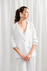 Blazer de lino blanco con estampado floral en tonos rosa y verde, corte holgado, cuello solapa y bolsillos laterales.