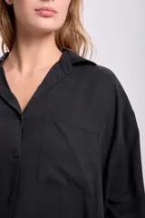 Camisa negra de lyocell, corte amplio, con cuello clásico, cierre frontal con botones, manga larga y bolsillo de parche en el pecho.
