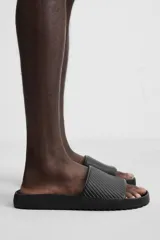 Sandalias tipo pala color beige con tira ancha en el empeine con relieve y suela de goma con volumen.