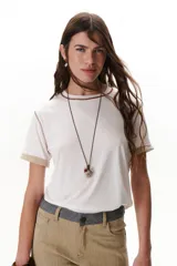 Remera blanca de algodón con cuello redondo, mangas cortas con dobladillo y costuras a contratono en color marrón.