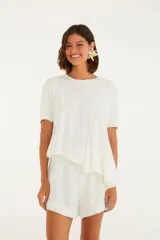 Remera blanca de corte amplio con cuello redondo, manga corta y detalles de costuras en el frente.