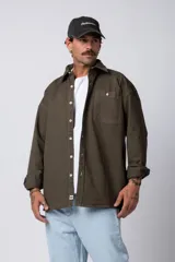 Camisa verde militar de manga larga, corte oversize, con cuello clásico, cierre frontal con botones y bolsillo en el pecho. Confeccionada en algodón suave y con costuras a la vista.