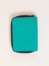 Billetera fucsia con cierre de cremallera y parche de goma negro con logo.