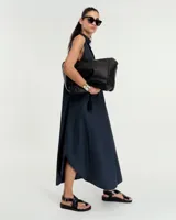 Vestido evasé sin mangas confeccionado en denim liviano, con cuello mao y falsa cartera que forma un escote en V con tabla central delantera. Posee bolsillos laterales, tablón en el centro de la espalda y ruedo redondeado con tajos laterales. Largo hasta mitad de la pantorrilla.