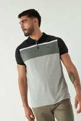Remera tipo polo de manga corta con diseño a bloques de color: negro en cuello y mangas, gris oscuro en la parte superior del pecho, blanco en el centro y gris claro en el resto del cuerpo.