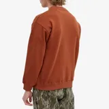 Sweater marrón de corte holgado con cuello redondo y logo estampado en verde.