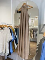 Vestido largo confeccionado en 100% lino, con cuello halter y silueta fluida en color beige.