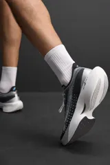 Zapatilla deportiva para correr largas distancias, color gris y negro, con parte superior de tejido de punto transpirable y suela de TPE-A. Cuenta con placa de carbono interna, plantilla interior OrthoLite®, stack de 39 mm y drop de 8 mm. Marca Zara Athleticz.