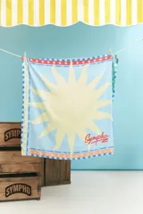 Pañuelo cuadrado de poliéster color rojo con diseño de sol celeste y blanco. Tiene borde con texto "Charrúa Uruguay Since 2015" y estrellas.