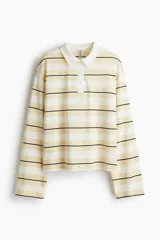 Remera polo de manga larga con rayas horizontales en tonos blanco, amarillo y negro. Tiene cuello clásico y tapeta con botones.