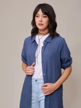 Vestido camisero largo azul, confeccionado en lino y algodón. Tiene cuello camisero, mangas cortas con trabillas y cierre frontal con botones.