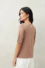 Remera de modal color marrón claro, de manga corta, con cuello asimétrico y detalle de nudo con frunces.