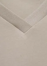 Camiseta blanca de algodón regenerativo, con cuello pico y manga corta.