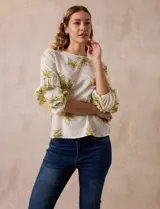 Blusa de gasa color crema con estampado de flores amarillas, de la marca Sioni. Tiene mangas 3/4 con volados y cuello redondo.