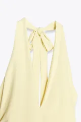 Vestido largo color amarillo pálido, con cuello halter que se ata en la nuca, escote en pico y frunces laterales.