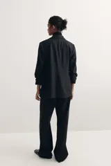 Blazer negro entallado confeccionado en mezcla de viscosa, con hombreras, solapas de muesca, mangas tres cuartos fruncidas y bolsillos delanteros con solapa. Sin cierre.