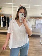 Blusa celeste de lino con cuello en V, mangas cortas con dobladillo y cierre lateral con botones de madera.