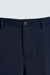 Pantalón de vestir azul marino, de corte slim fit, con bolsillos laterales y traseros. Se ajusta a la cintura con cinturón de cuero marrón.