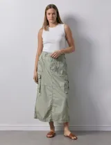 Falda larga color beige, de corte recto, con bolsillos cargo laterales y traseros, pretina con pasadores, botón y cierre.