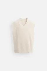 Chaleco de punto color crema con cuello en V y sisas amplias.