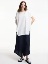 Remera blanca de algodón, corte amplio y largo irregular con tajos laterales.