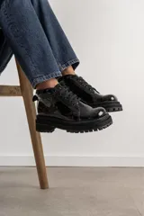 Borcegos negros de cuero charol, con punta cuadrada, cordones y suela track.