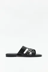 Sandalias bajas negras de símil cuero, con tiras asimétricas y apliques de tachas.