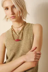 Musculosa de tejido calado color dorado, con cuello redondo y sisas amplias.