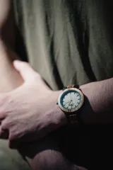 Reloj de pulsera con caja y esfera de madera clara, malla de madera oscura con incrustaciones de madera clara.