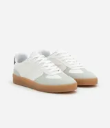 Championes urbanos de corte bajo, color blanco con detalles en gris y negro. Confeccionados en material sintético con recortes efecto gamuza y suela de látex color caramelo.