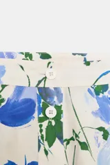 Falda midi de tiro medio confeccionada en algodón con estampado floral en tonos azules y verdes. Tiene pliegues en la cintura, corte evasé y cierre frontal con botones.