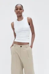 Pantalón color beige de tiro medio con trabillas, pliegues frontales y corte ancho.