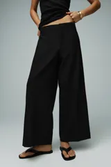 Pantalón negro de tiro medio con trabillas en la cintura, pernera recta y corte cropped. Cierre frontal con cremallera y ganchos metálicos.